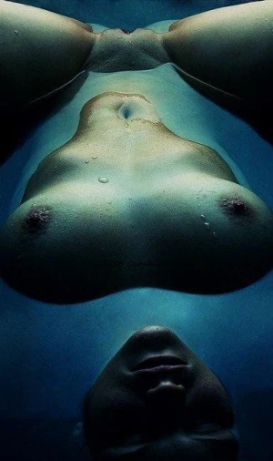 Interesting nude photograph aquatic blue floating on back with boobs and face above surface pussy submerged with  moon lighting effect.