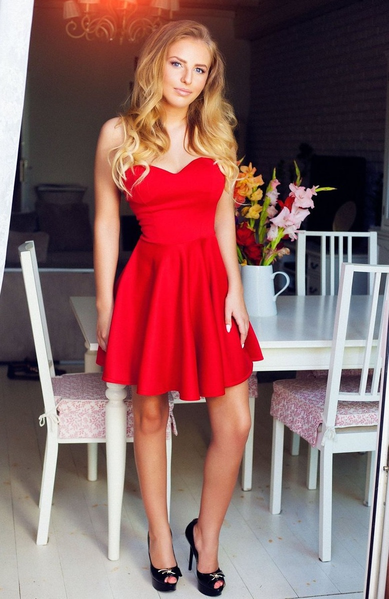 Hot blonde doll posing in sexy low cut red dress with exposed shoulders and some black high heeled open toe platforms